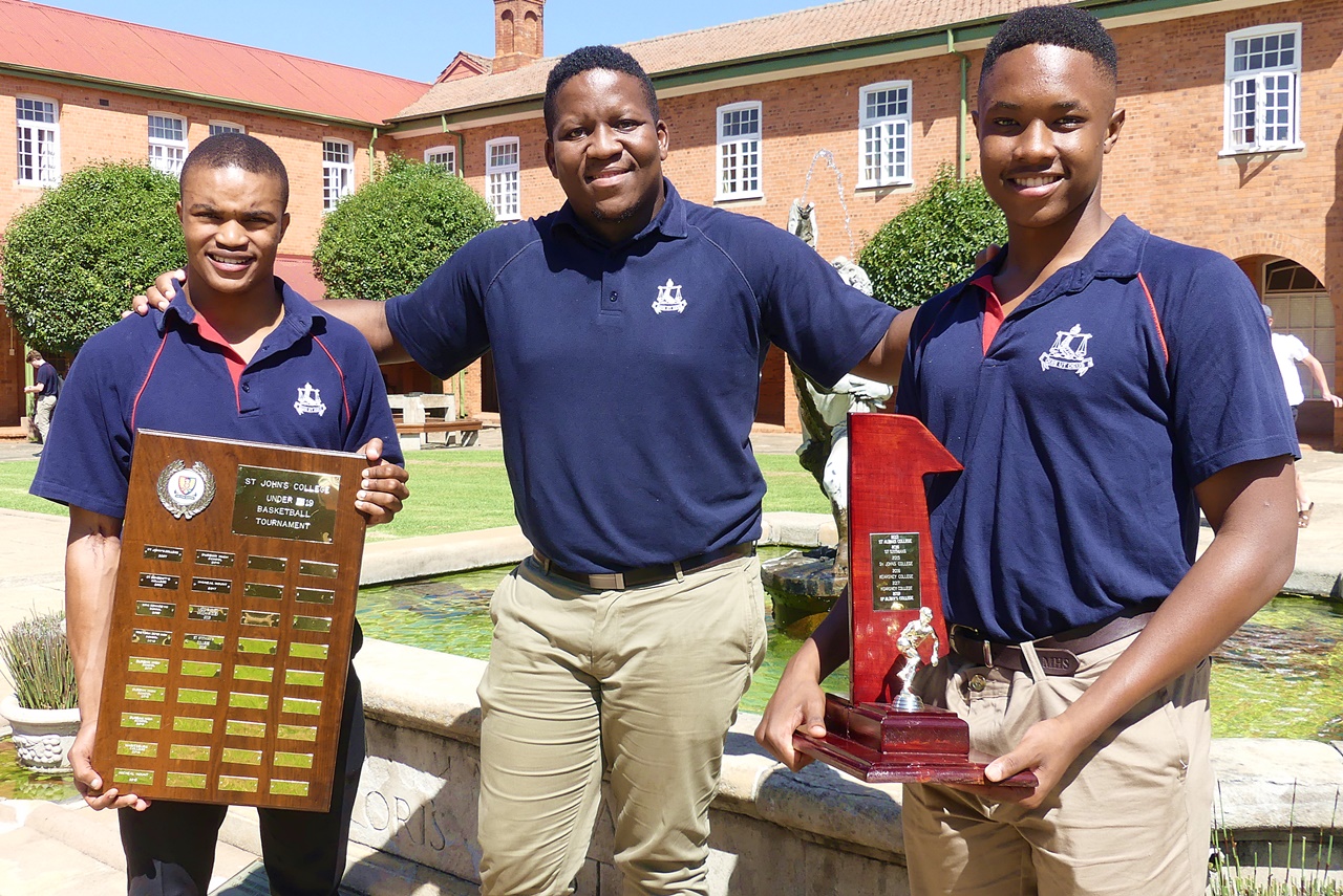 Point guard Banele Sithole with the Saint John’s Tournament Trophy, coach Nkanyiso Ngcobo, and shooting guard Jason Makhele with the Stayers’ Tournament Trophy. (Photo: Brad Morgan)