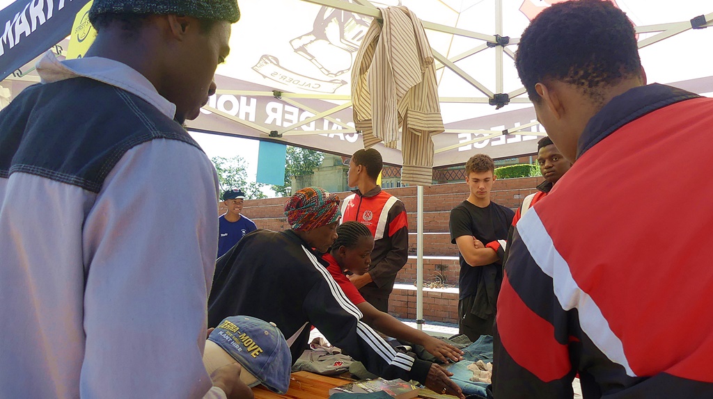 Maritzburg College Business Studies' boys watch as customers select clothing from one of their Street Store gazebos. (Photo: Brad Morgan)